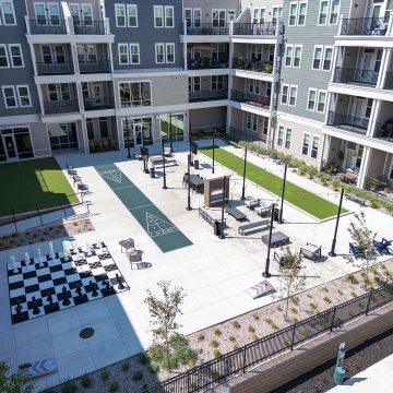 Aerial shot of the interior courtyard, featuring a life size chess board, two green areas and shuffle board court.