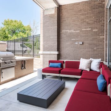 A grill lounge area with a built in propane grill and red sectional seating.