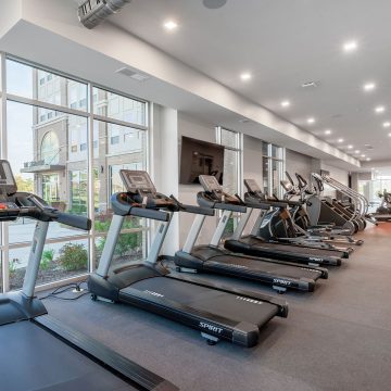 On site gym for The Signature At Carmel property showcasing a row of treadmills and stair climber machines.