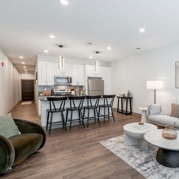 Modern kitchen and island with white cabinets, stainless appliances and black countertops.